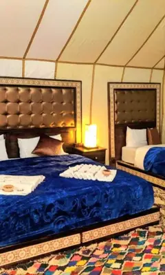 a bedroom with two beds in a tent at Habibi Luxury Camp in Merzouga