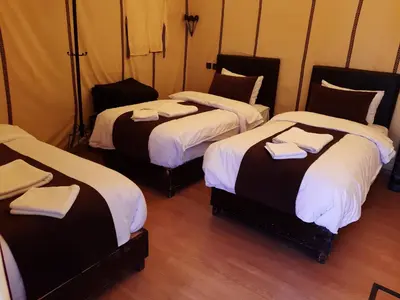 a room with three beds with towels on them at Camp fire Dreams in Merzouga
