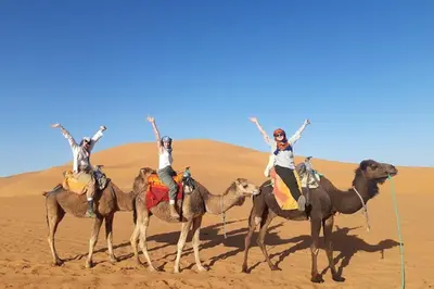 four people riding on camels in the desert at Camp fire Dreams in Merzouga