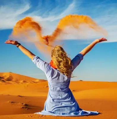 a woman in the desert with her arms outstretched at Desert camp nights camel ride in Merzouga