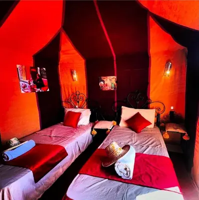 two beds in a room with red lighting at Desert camp nights camel ride in Merzouga