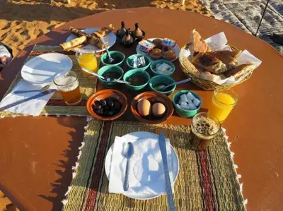 a table with food and drinks on top at Desert camp nights camel ride in Merzouga