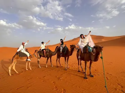 four people riding on camels in the desert at Desert camp nights camel ride in Merzouga