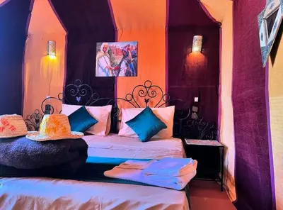 a bedroom with a bed with blue and pink at Desert camp nights camel ride in Merzouga