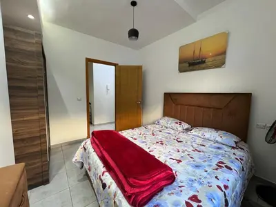 a bedroom with a bed with a red blanket on it at Beautiful apartment for rent in Oulad Akkou
