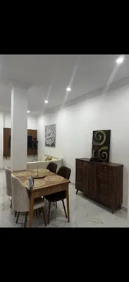 a living room with a wooden table and chairs at Hatim bien-être in Oulad Akkou