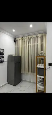 a kitchen with a refrigerator and a window with curtains at Hatim bien-être in Oulad Akkou