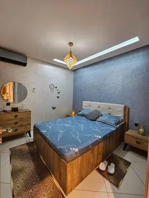 a bedroom with a bed and a blue wall at Hay mabroka in Oulad Akkou