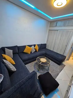 a living room with a blue couch and a table at Hay mabroka in Oulad Akkou
