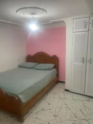 a bedroom with a bed and a pink wall at منزل العمراني in Oulad Akkou