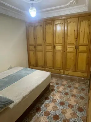 a bedroom with a bed and wooden cabinets at منزل العمراني in Oulad Akkou