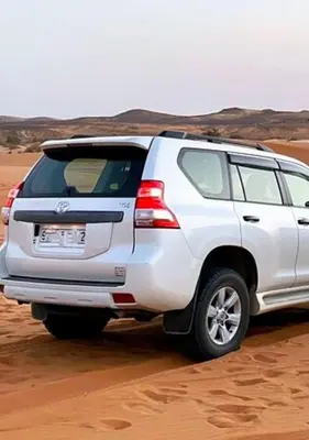 a white suv parked in the desert at Merzouga in Oulad Akkou