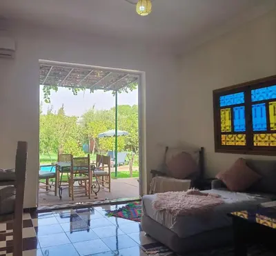 a living room with a bed and a table and a patio at Charming Villa with Pool in Amekhlig