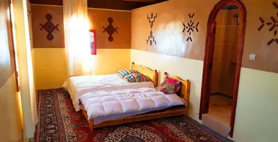 a bedroom with a bed in the corner of a room at hotel boutaghrar in Bou Tharar