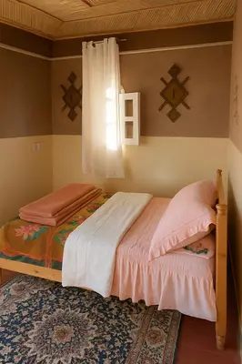 a bedroom with two beds and a window at hotel boutaghrar in Bou Tharar