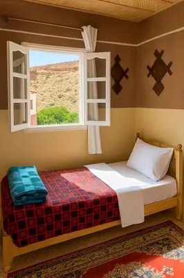 a small bed in a room with a window at hotel boutaghrar in Bou Tharar