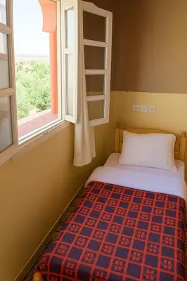 a bed in a room with a window at hotel boutaghrar in Bou Tharar