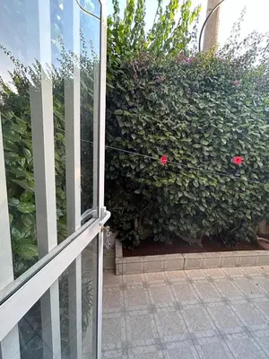 a glass door of a building with a bush with pink flowers at Agadir apartment with garden near Souk El Had in Oulad Akkou