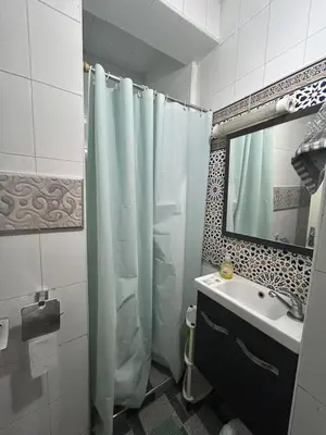 a bathroom with a shower curtain and a sink at Agadir apartment with garden near Souk El Had in Oulad Akkou