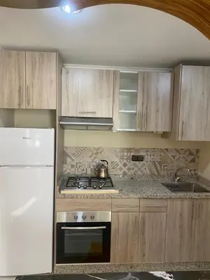 a kitchen with wooden cabinets and a stove top oven at Agadir apartment with garden near Souk El Had in Oulad Akkou