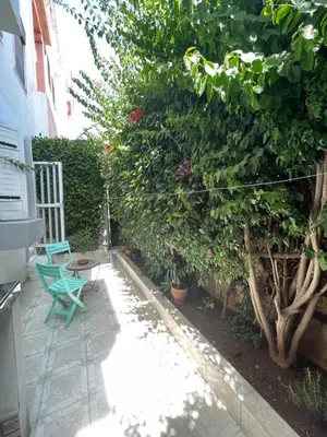 a patio with a green chair and some plants at Agadir apartment with garden near Souk El Had in Oulad Akkou