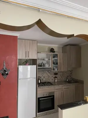 a kitchen with a white refrigerator and wooden cabinets at Agadir apartment with garden near Souk El Had in Oulad Akkou