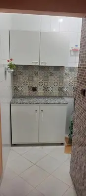 a kitchen with white cabinets and a tile wall at Agadir apartment with garden near Souk El Had in Oulad Akkou
