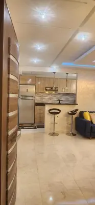 a kitchen with a refrigerator and a table and a couch at مفتاح الساحل انزا in Oulad Akkou