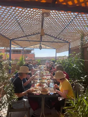 a group of people sitting at a long table at Raid rooftop atlas dades in Boumalne