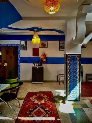 a living room with blue and white walls and a red rug at Raid rooftop atlas dades in Boumalne
