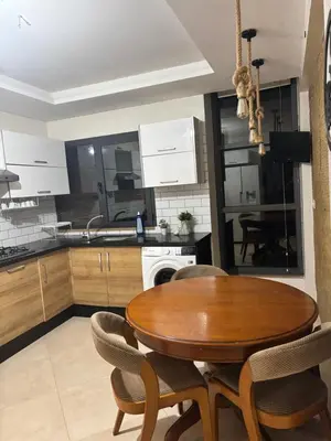 a kitchen with a wooden table and chairs in a kitchen at Appartement spacieux in Oulad Akkou