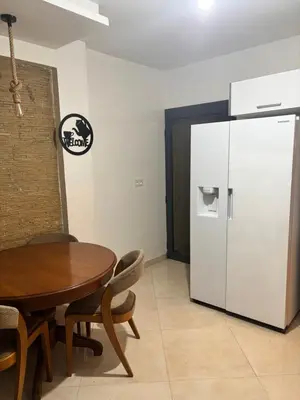 a dining room with a table and a refrigerator at Appartement spacieux in Oulad Akkou