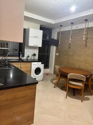 a kitchen with a table and a sink and a washing machine at Appartement spacieux in Oulad Akkou