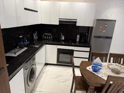 a kitchen with white cabinets and a table and a refrigerator at Mehdia plage apparemment in Oulad Akkou