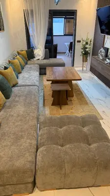 a living room with a large couch and a coffee table at Mehdia plage apparemment in Oulad Akkou