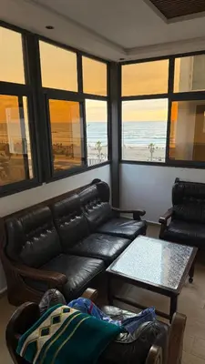 a living room with a leather couch and a table at Mehdia plage apparemment in Oulad Akkou