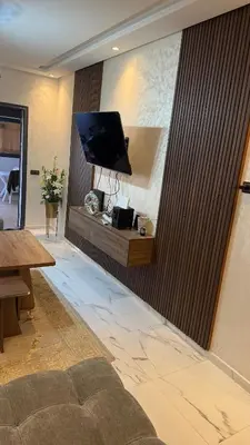 a living room with a couch and a tv on a wall at Mehdia plage apparemment in Oulad Akkou