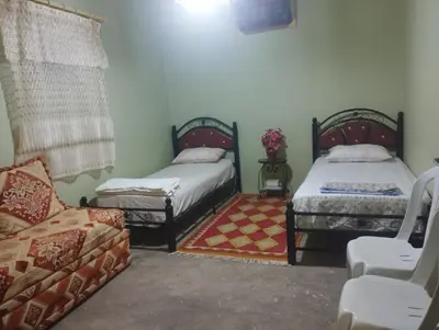 a room with two beds and a chair and a couch at Dar dyafa in Oulad Akkou