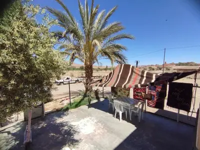 a patio with a table and a palm tree at Dar dyafa in Oulad Akkou