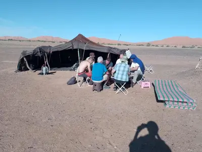 a group of people sitting in front of a tent at Emosion desert trekking in Hassilabied