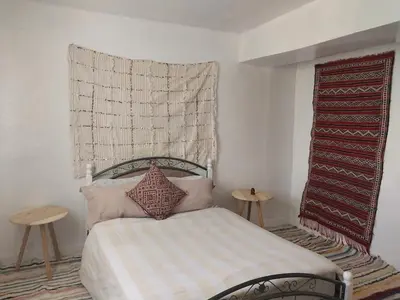 a bedroom with a bed with a blanket and two tables at Gite Montana in Aïn Leuh
