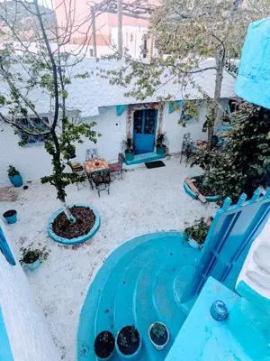 a blue patio with a tree and a blue chair at Gite Montana in Aïn Leuh