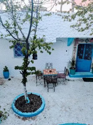 a table and chairs and a tree in front of a house at Gite Montana in Aïn Leuh