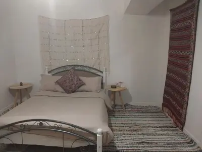 a bedroom with a bed with a headboard and two tables at Gite Montana in Aïn Leuh