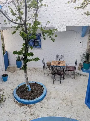 a table and chairs and a tree in a courtyard at Gite Montana in Aïn Leuh