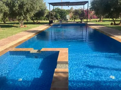 a swimming pool with blue water in a park at Villa Yassin Private Pool and Terrace in Marrakech