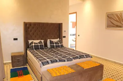 a bedroom with a large bed and a ottoman at Villa Yassin Private Pool and Terrace in Marrakech