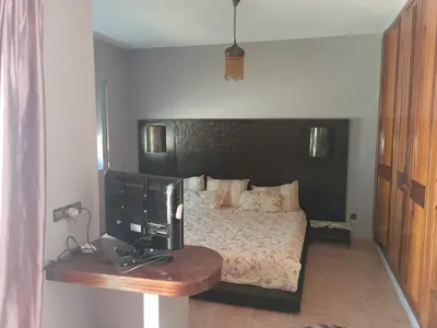 a bedroom with a bed and a desk with a television at فيلا بالصخيرات in Oulad Akkou