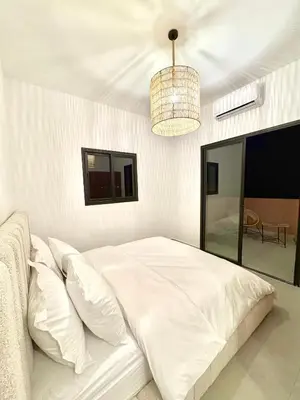 a white bedroom with a bed and a chandelier at Villa Elysia in Chaibate