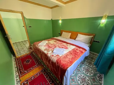a bedroom with a bed in a room with a mirror at Tabourihte Gardens in Tinerhir